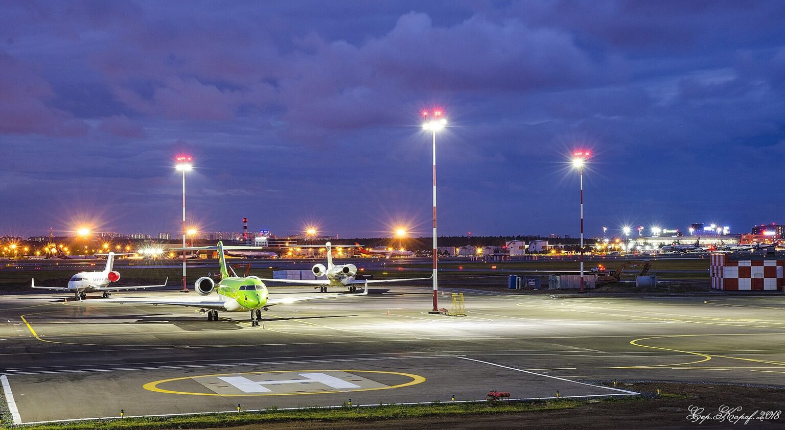 夕暮れの駐機場。着陸灯と誘導灯が、ひとつずつ灯りはじめる