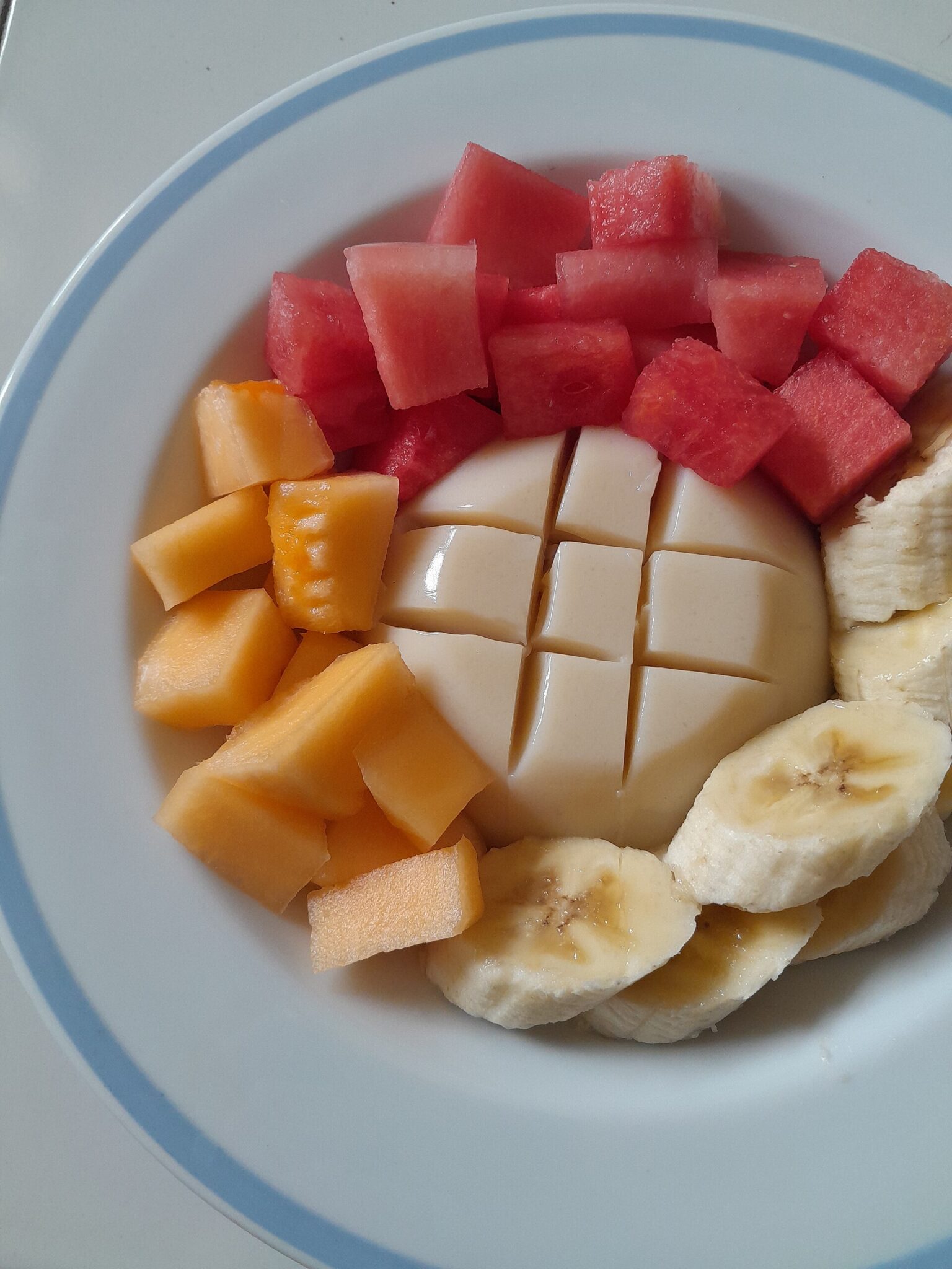 スイカやバナナを添えた冷たい豆腐プリン（タイの甘味として撮影されたもの）