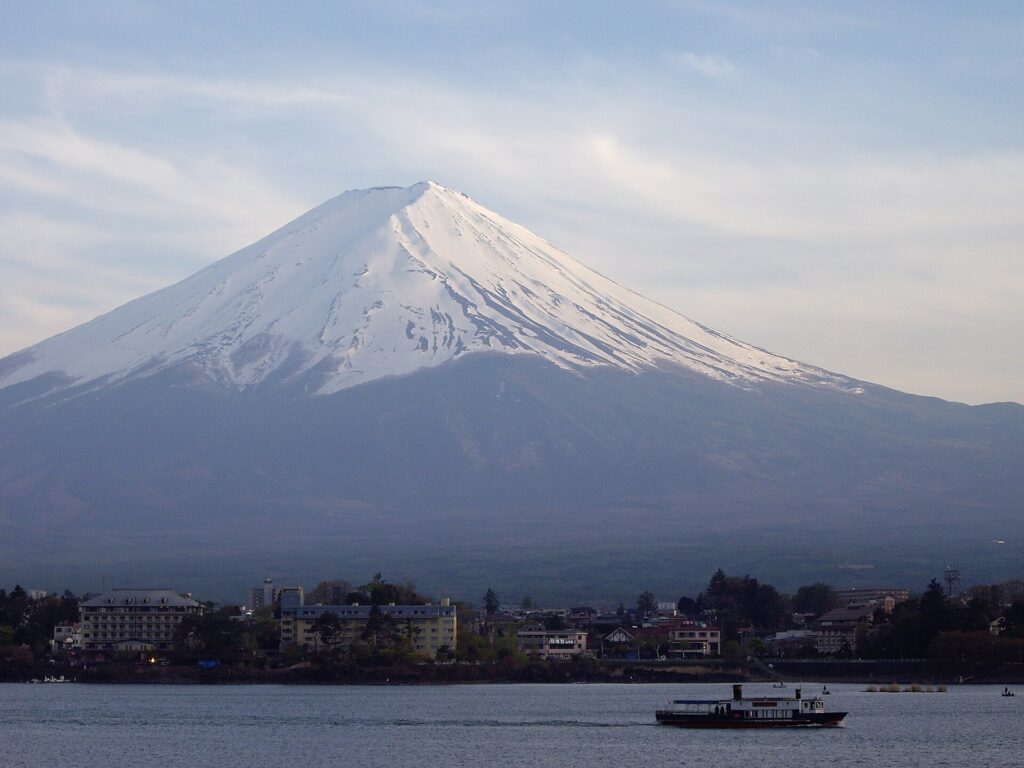 冬の河口湖。雪をかぶった山と湖畔の町、遊覧船
