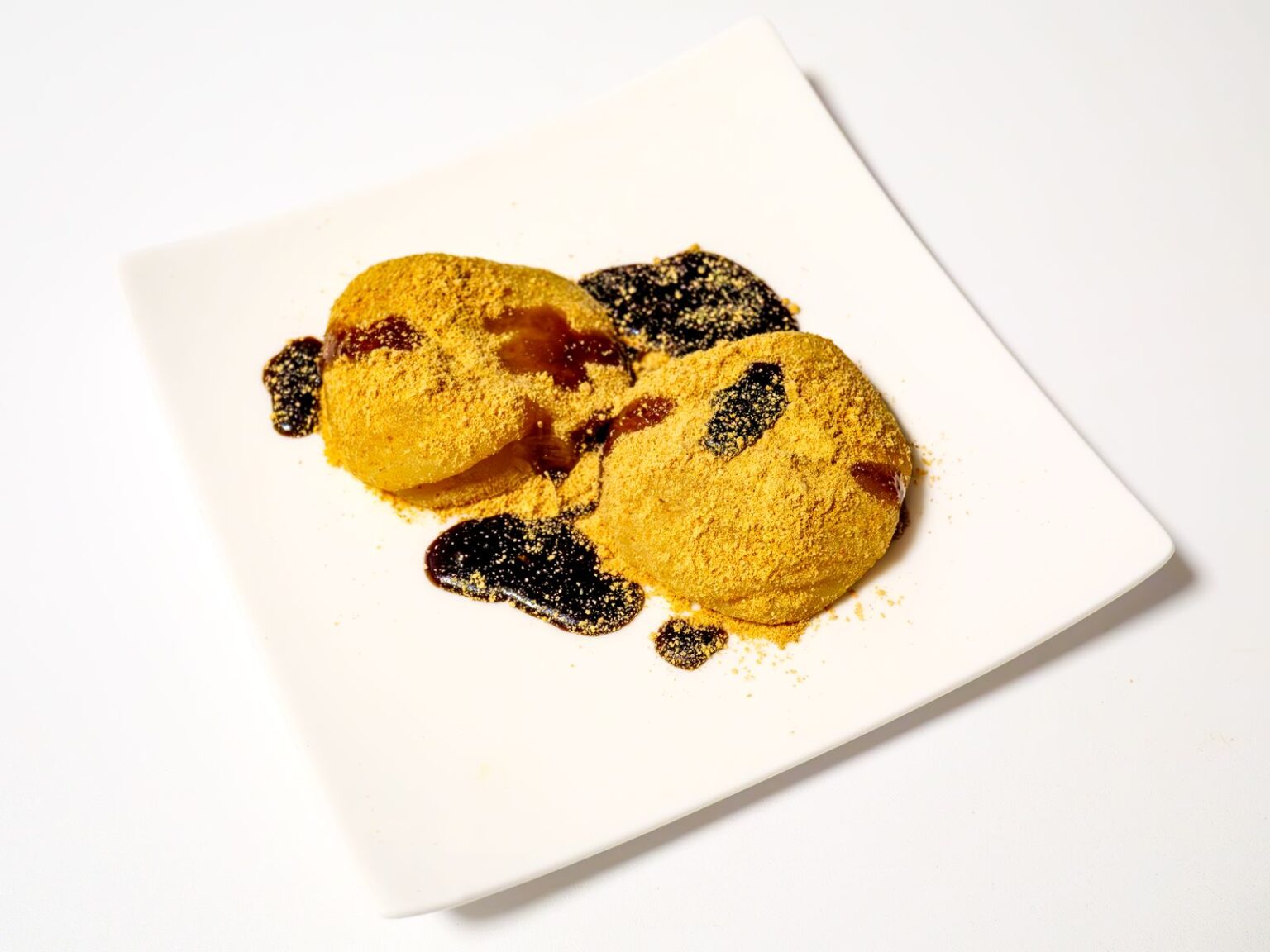 きな粉をまぶした餅に黒蜜をかける