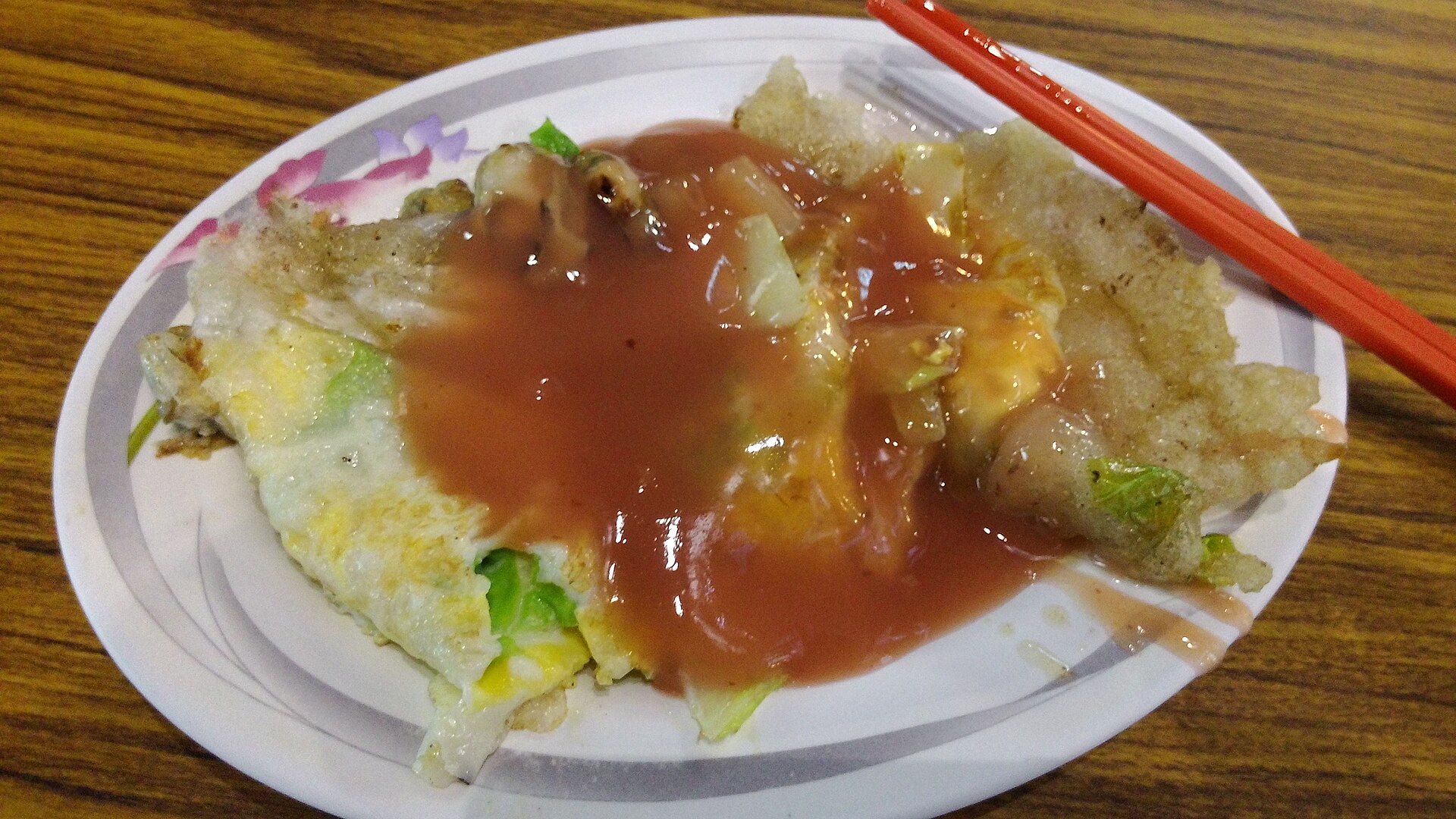 蚵仔煎のクローズアップ。青菜の緑と赤いタレ