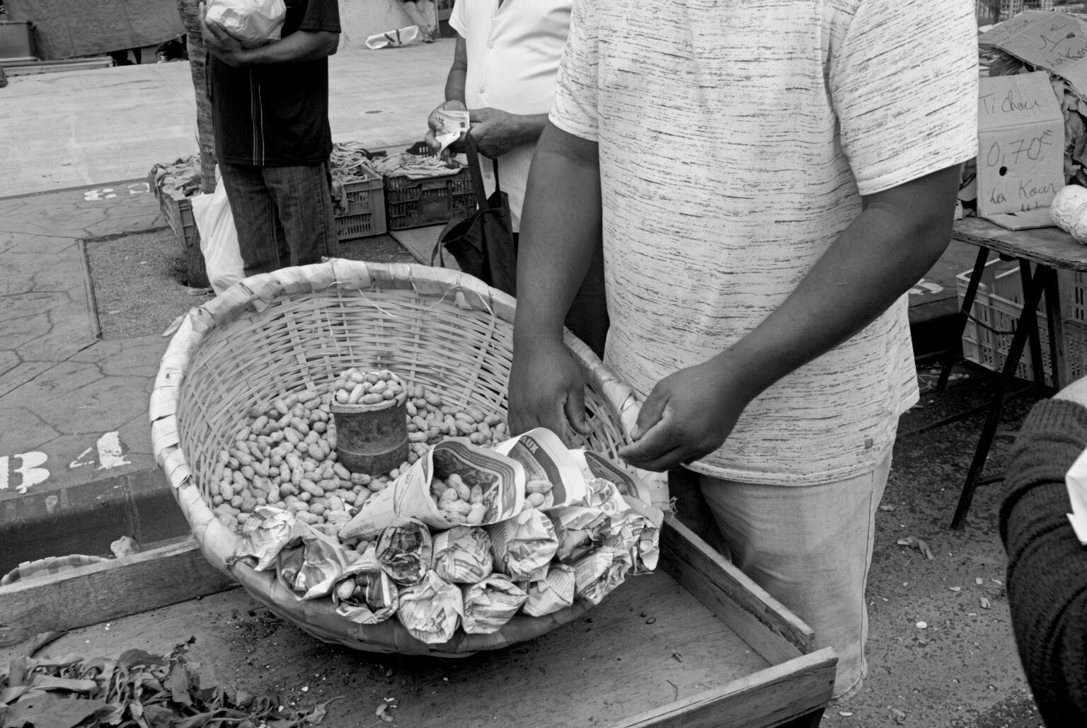 かごに入った炒りピスターシュ（落花生）を紙包みで売る露天商（白黒写真）
