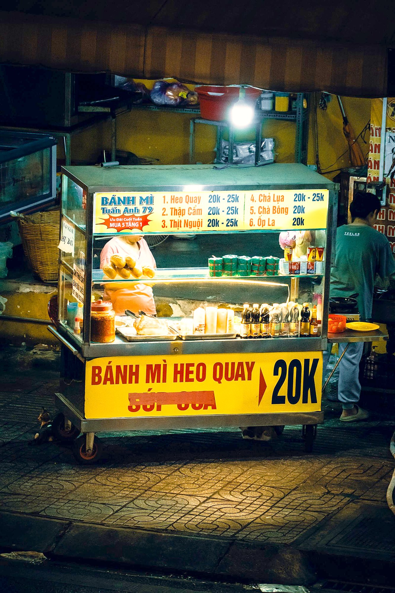 夜のバインミー屋台。「BÁNH MÌ HEO QUAY 20K」の黄色い品書き