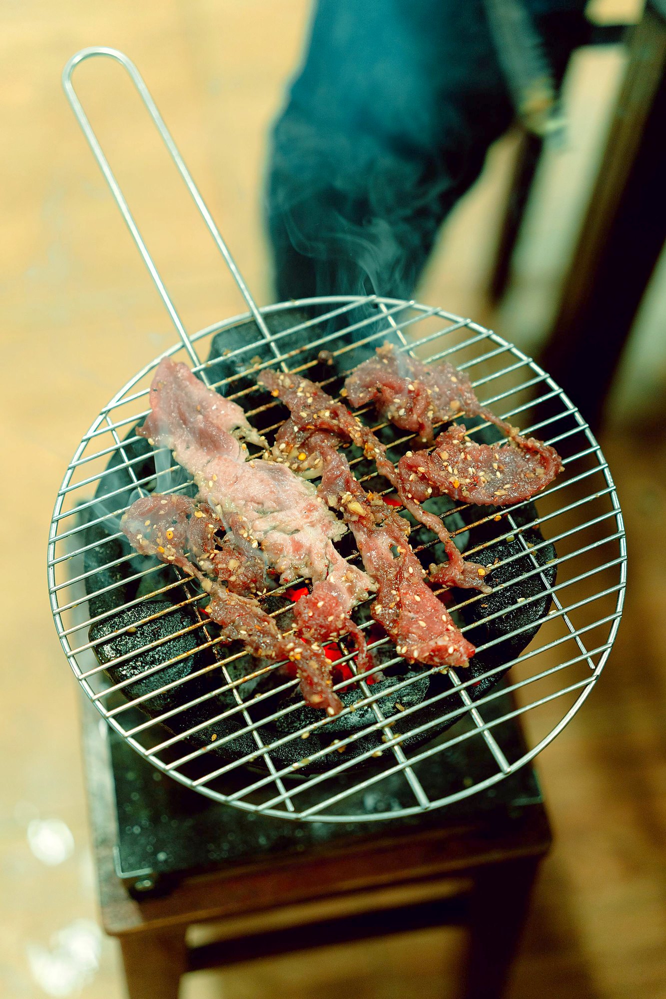 炭火の網の上で焼かれている、薄切りの豚肉