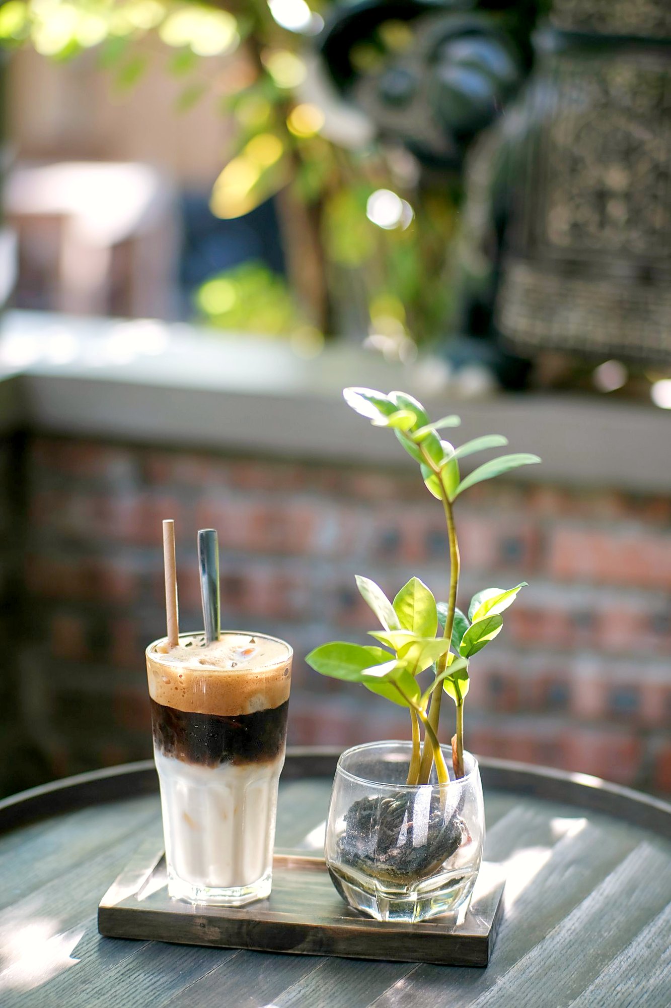 カフェの卓に置かれた背の高いグラス。下が白、上が濃い茶色の二層になっている