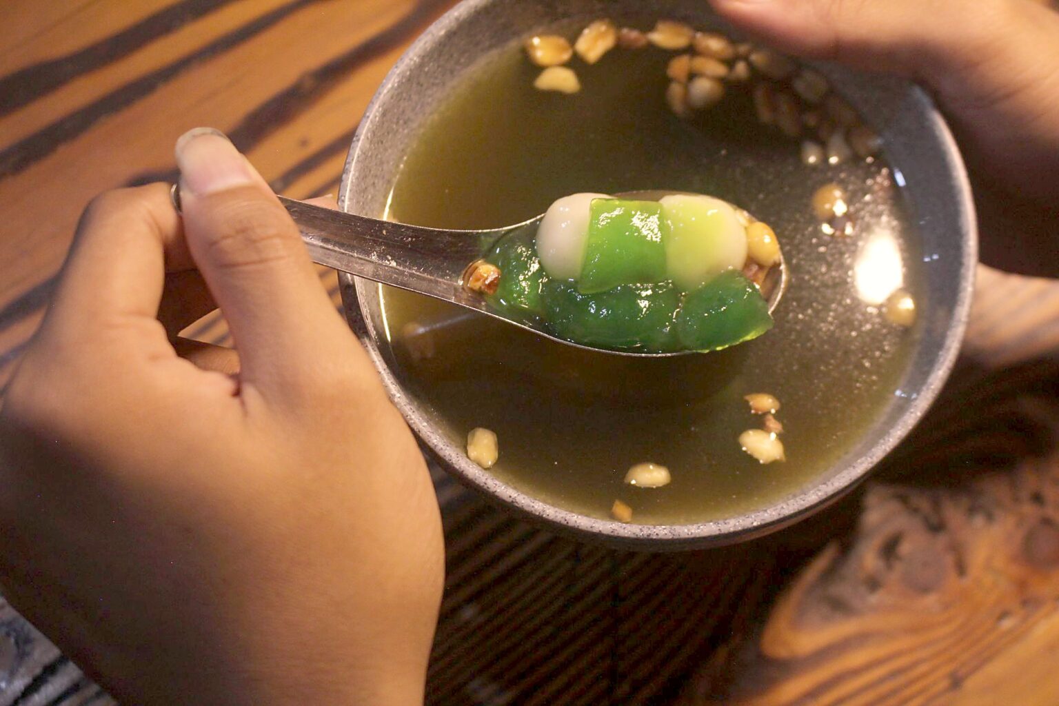 スプーンですくわれた、緑豆と白玉の入った甘い汁