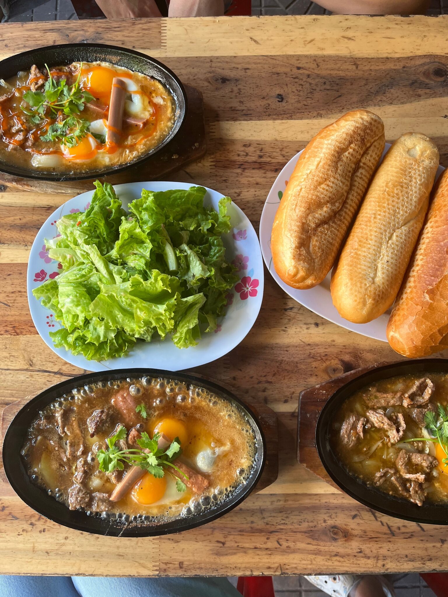 bò né。鉄板の上で焼ける牛肉と目玉焼き、bánh mìとレタス