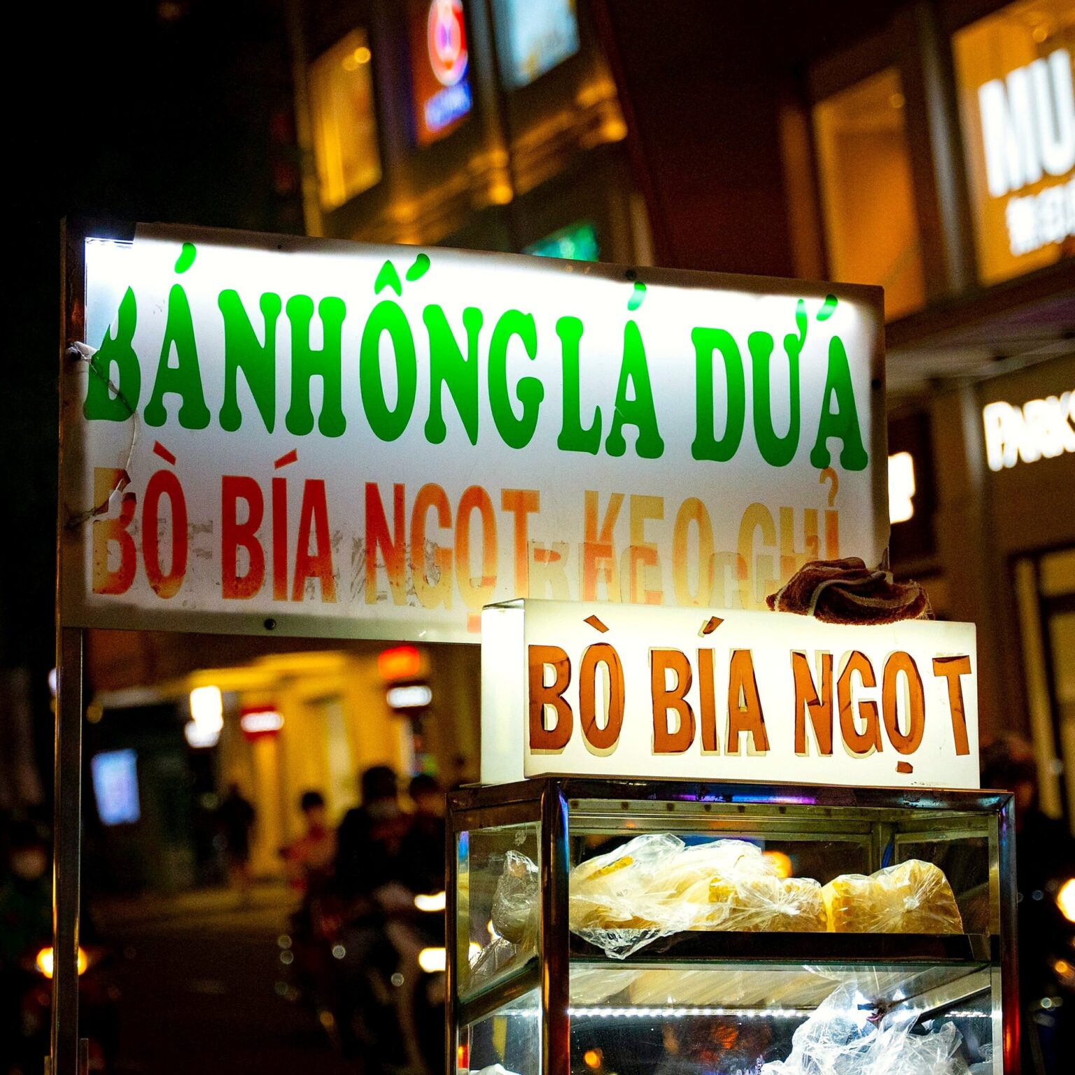 夜の屋台の看板「BÒ BÍA NGỌT・BÁNH HỒNG LÁ DỨA」