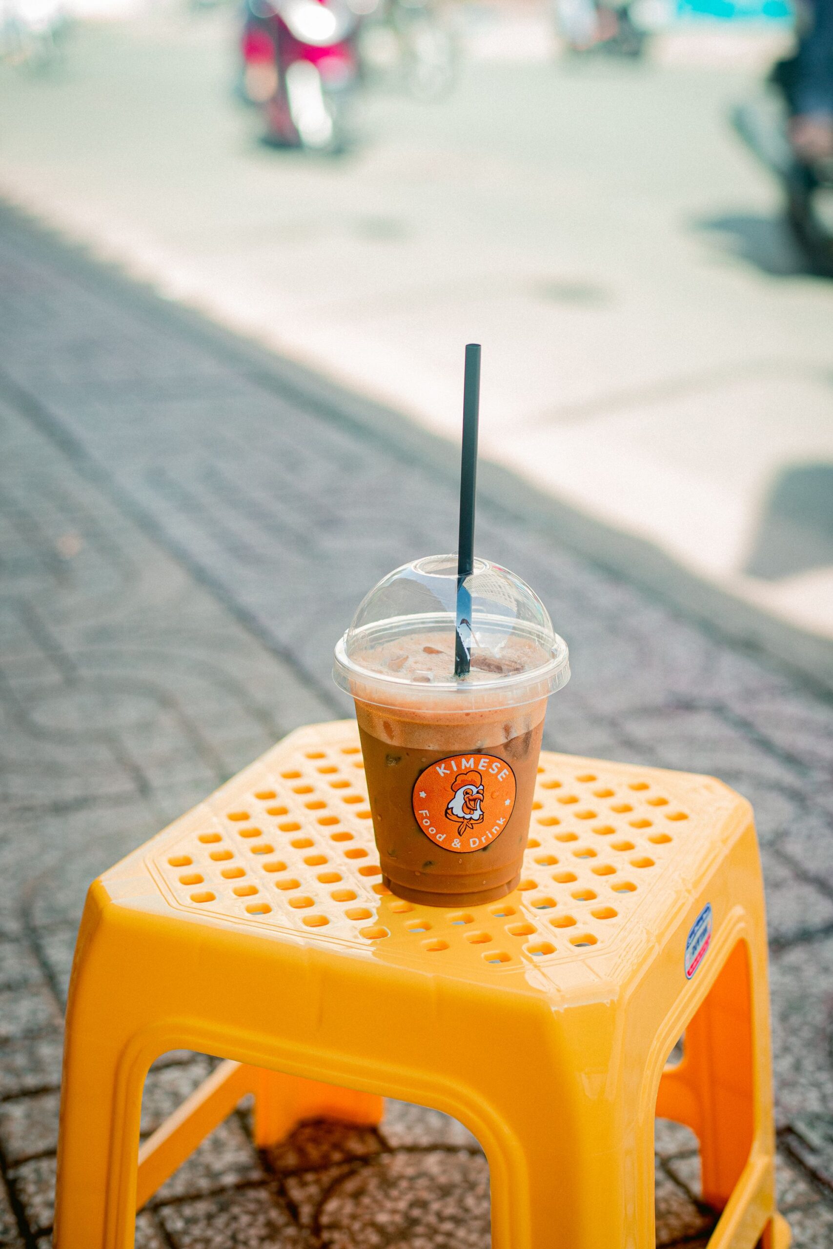 オレンジのプラスチック椅子に置かれたアイスコーヒー