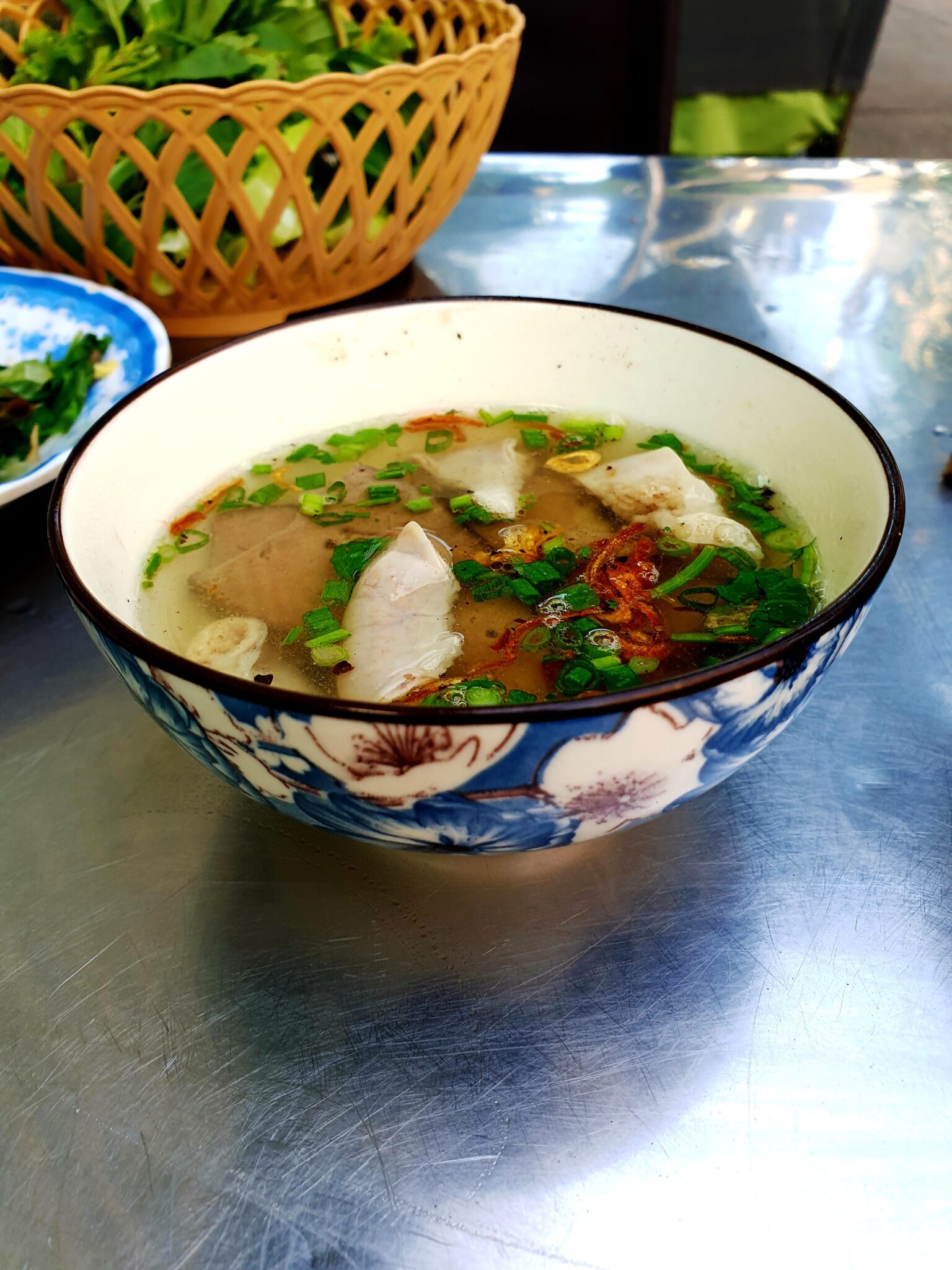 花柄の丼にフーティウ・ミトー。レバー、唐辛子。奥に籐かごの香草