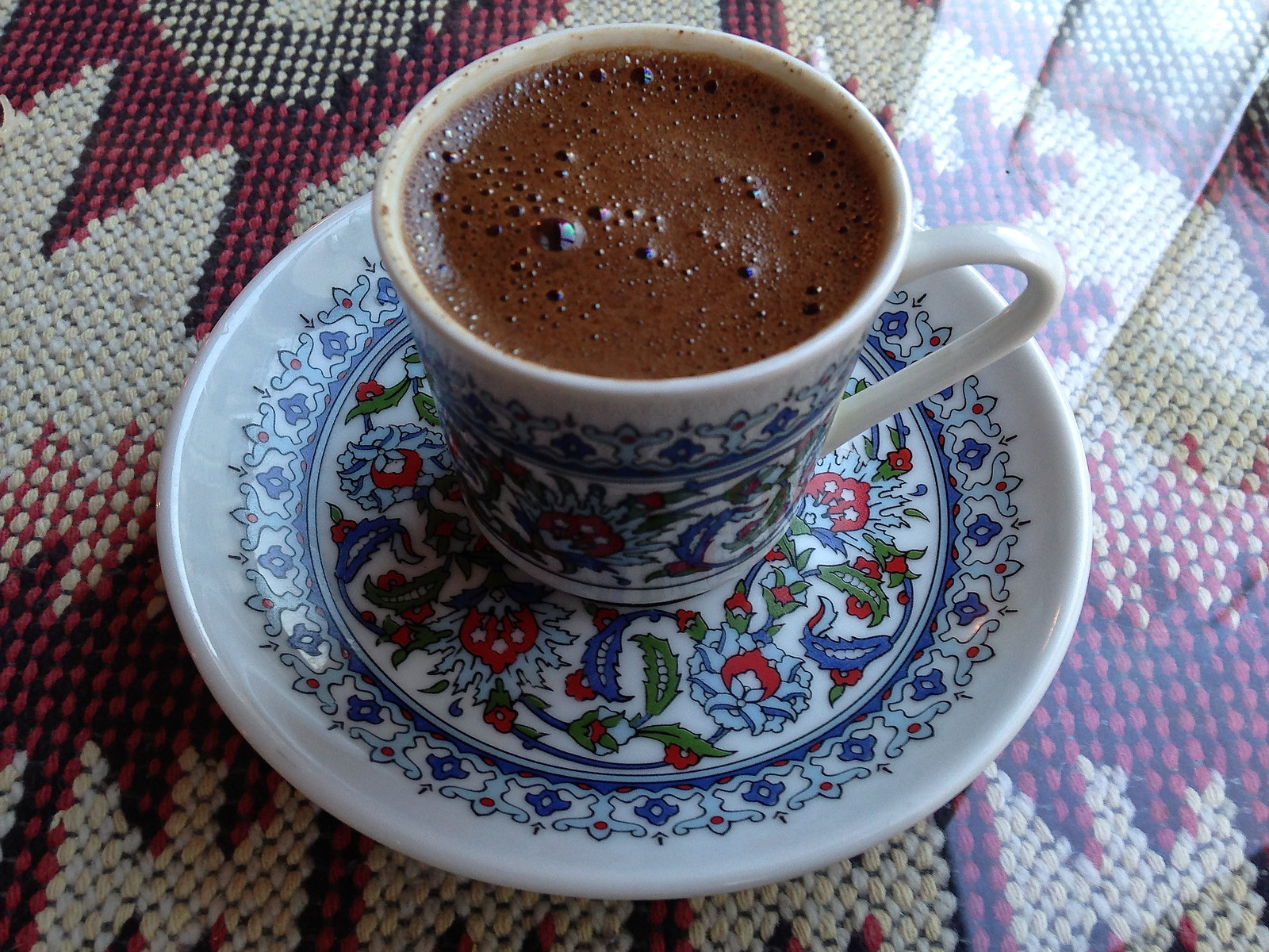チューリップ柄のカップと受け皿に入ったトルココーヒー、表面にきめ細かい泡