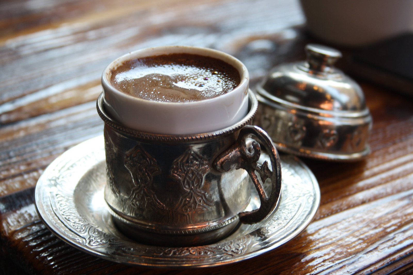 銀細工のホルダーに入ったトルココーヒーと蓋つきの砂糖入れ、木のテーブル