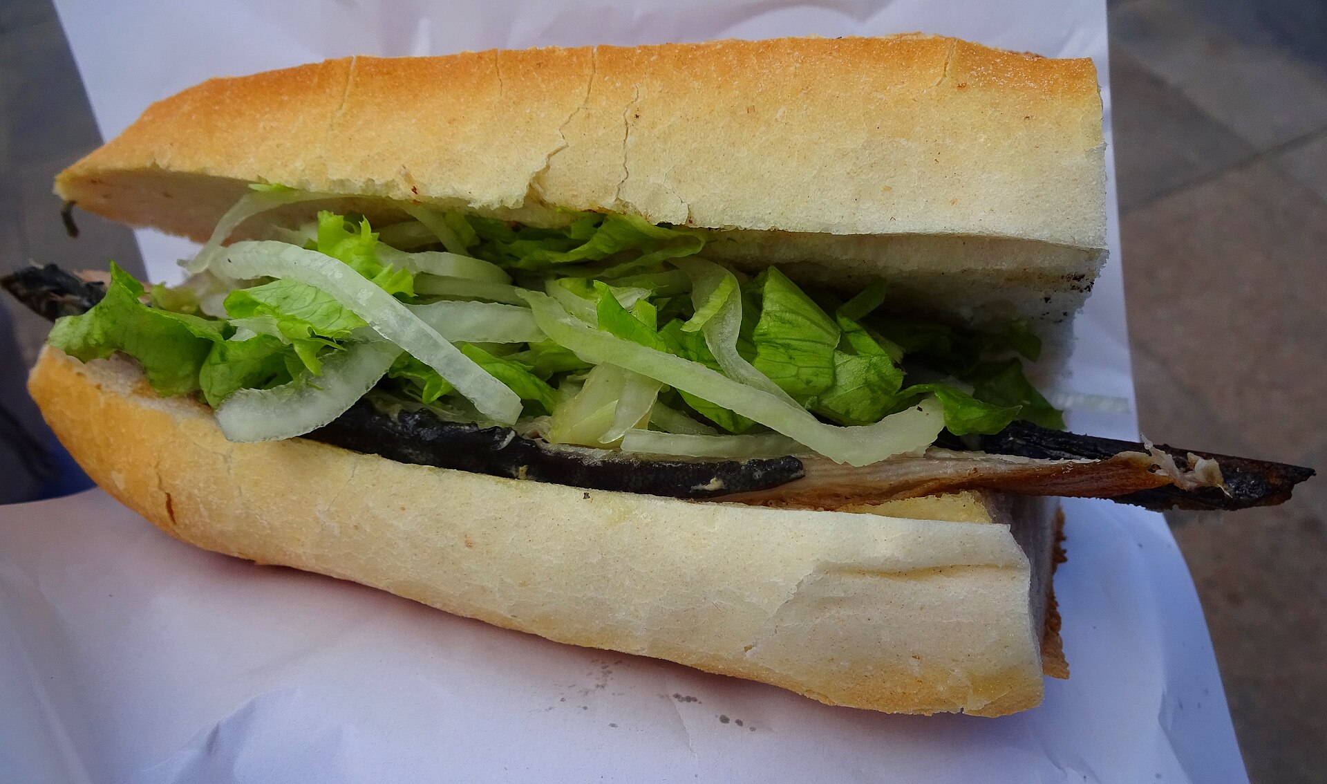 焼いたサバの半身を挟んだバゲット、レタスと薄切り玉ねぎ入りのサバサンド
