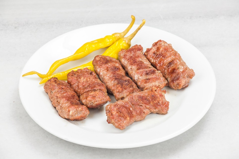 白い皿の焼きキョフテ5本と黄色い唐辛子