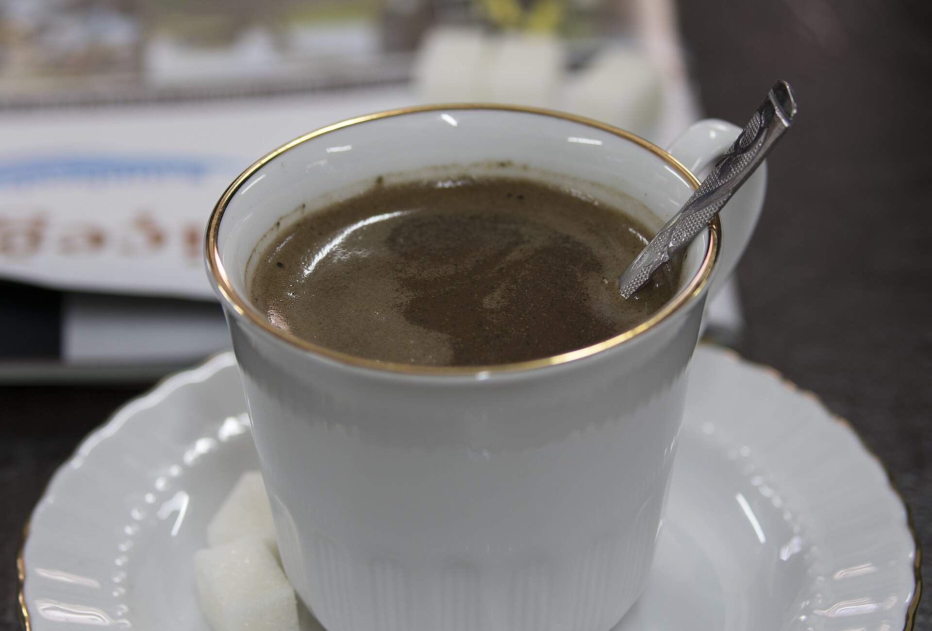 白いカップに入った泡立つメネンギチ・コーヒー、受け皿にスプーン