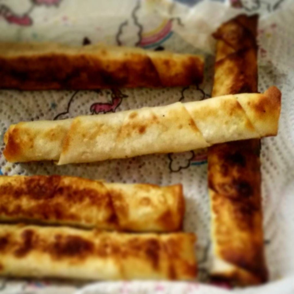紙の上に並ぶこんがり焼き色のついた細長いスィガラ・ボレイ