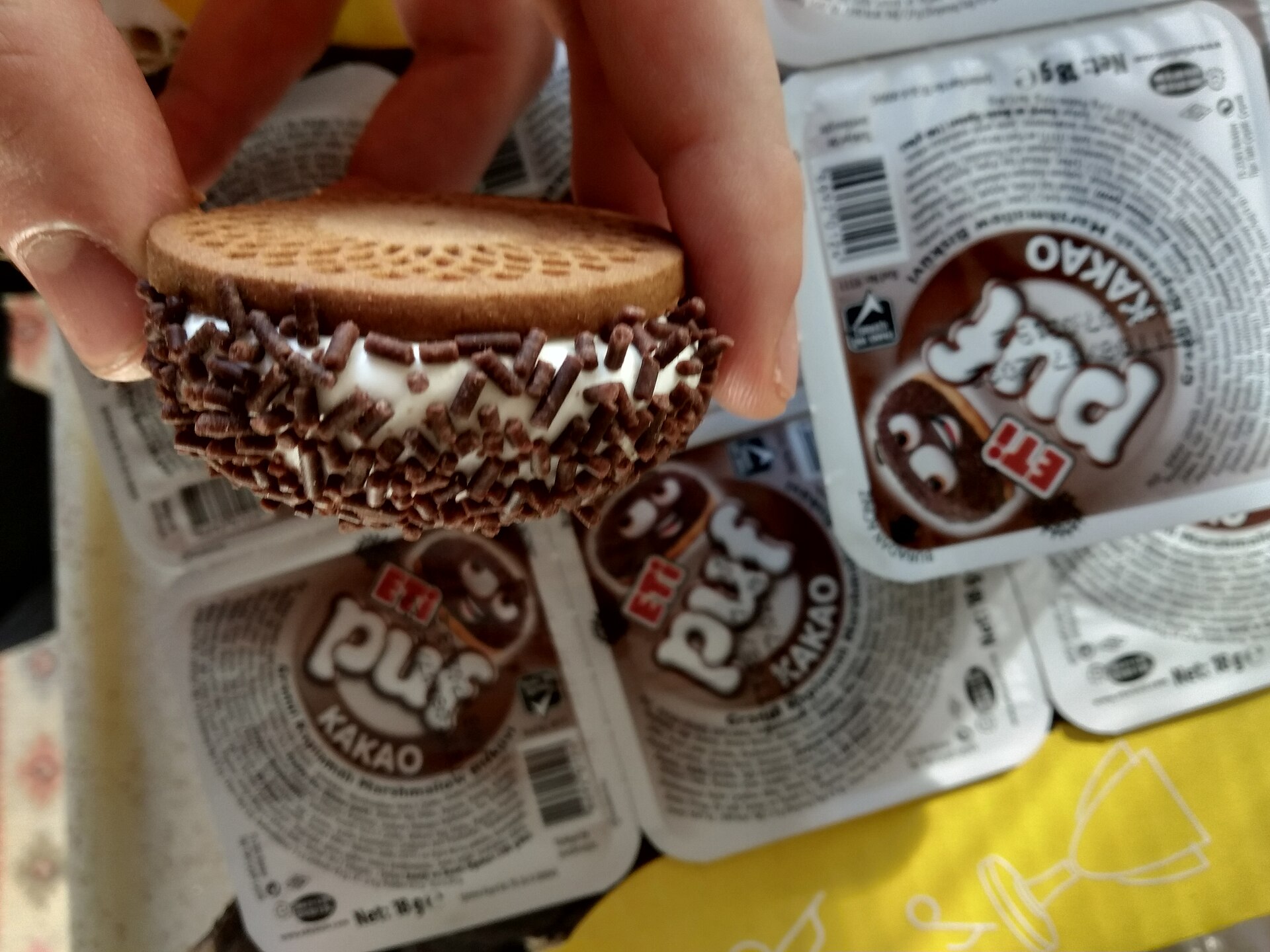指でつまんだ Eti Puf。ビスケットの上のマシュマロにチョコスプレー