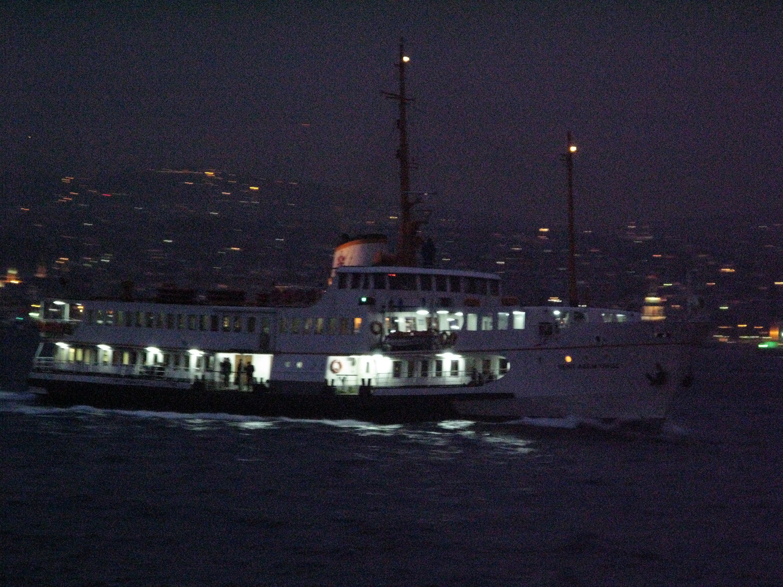夜のボスポラス海峡を窓明かりをともして進む市営フェリー