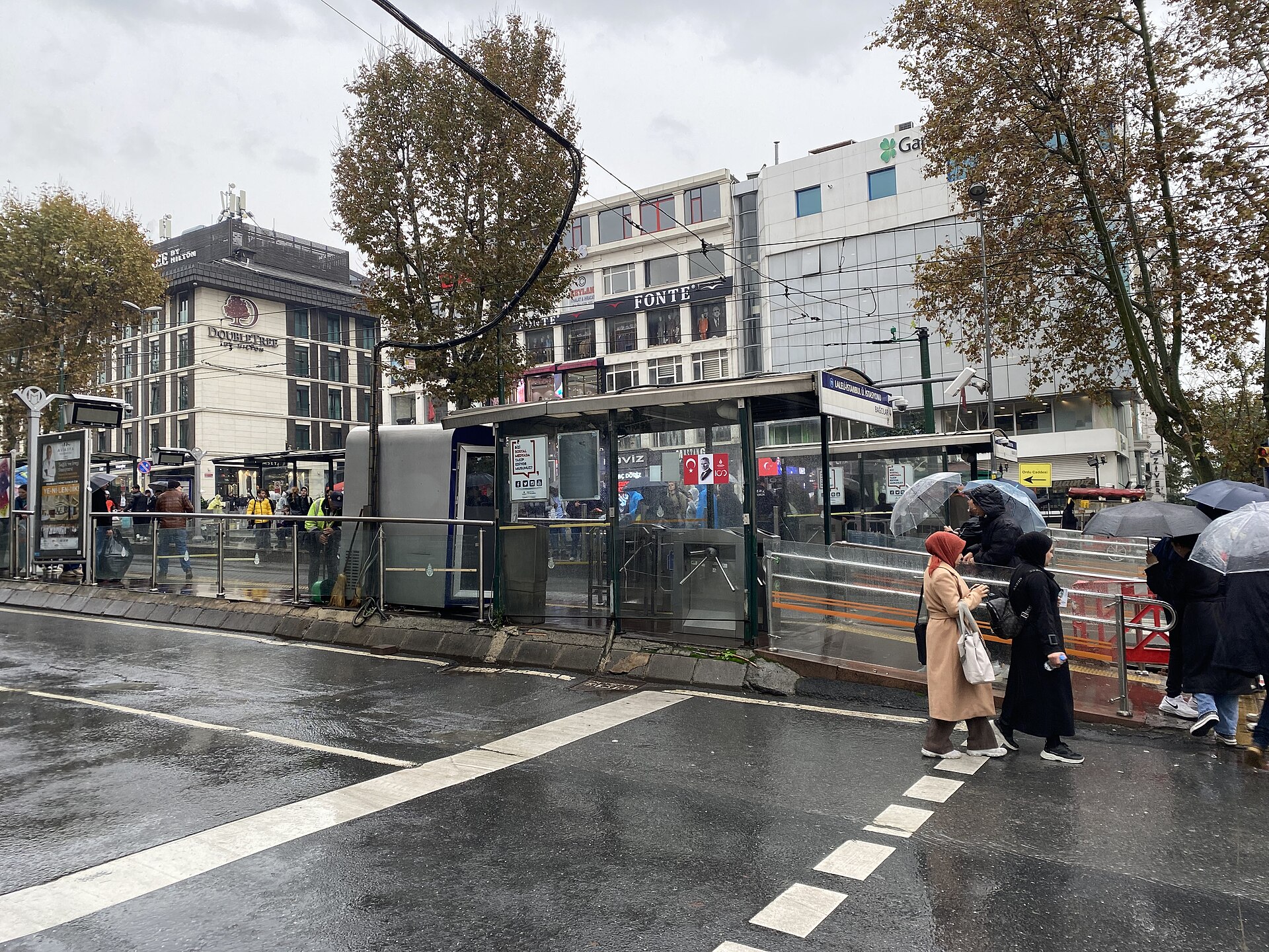 雨のラレリの大通りとトラムの停留所、傘をさす人