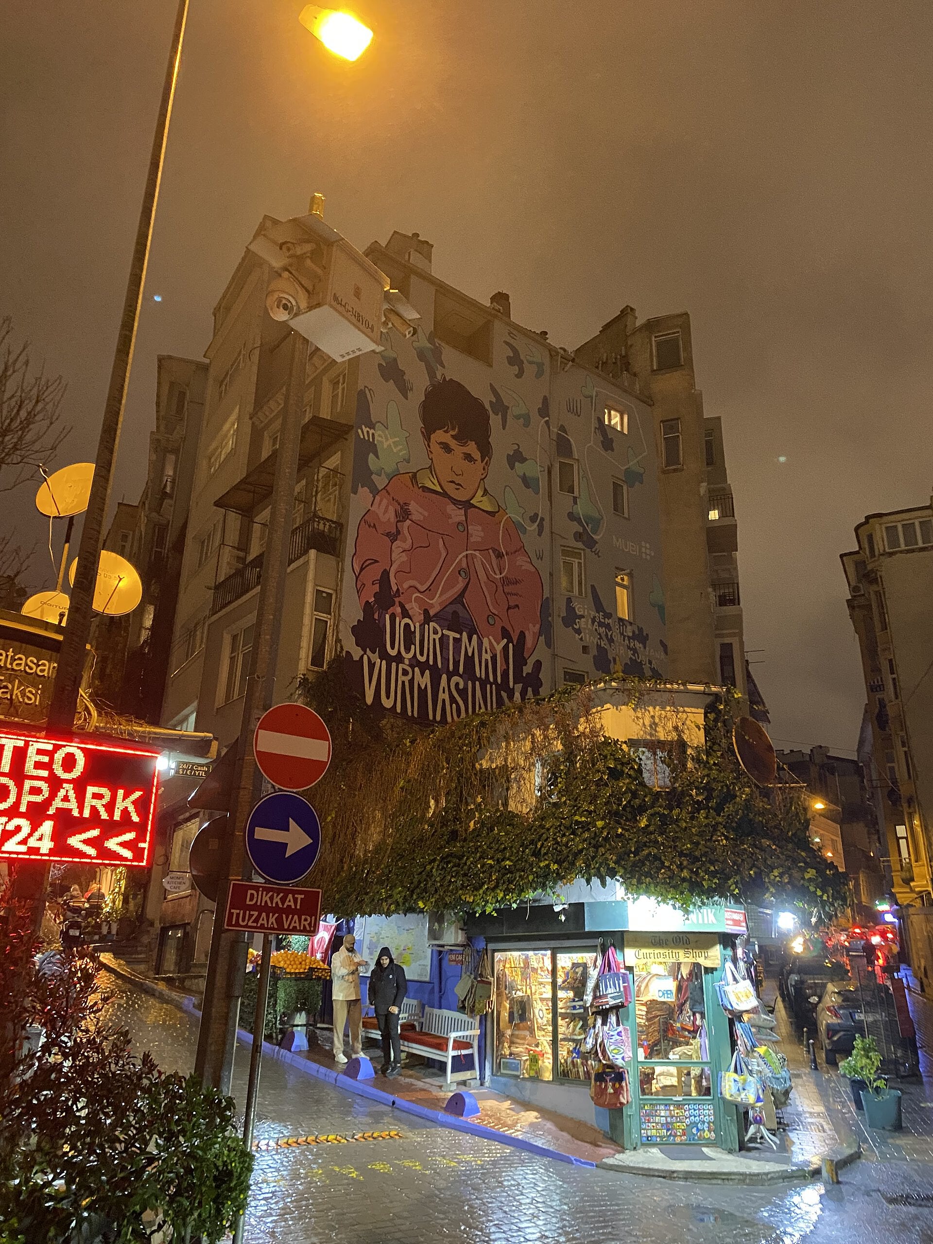 雨上がりの夜のベイオウルの角、壁画のある建物と灯りのともる店
