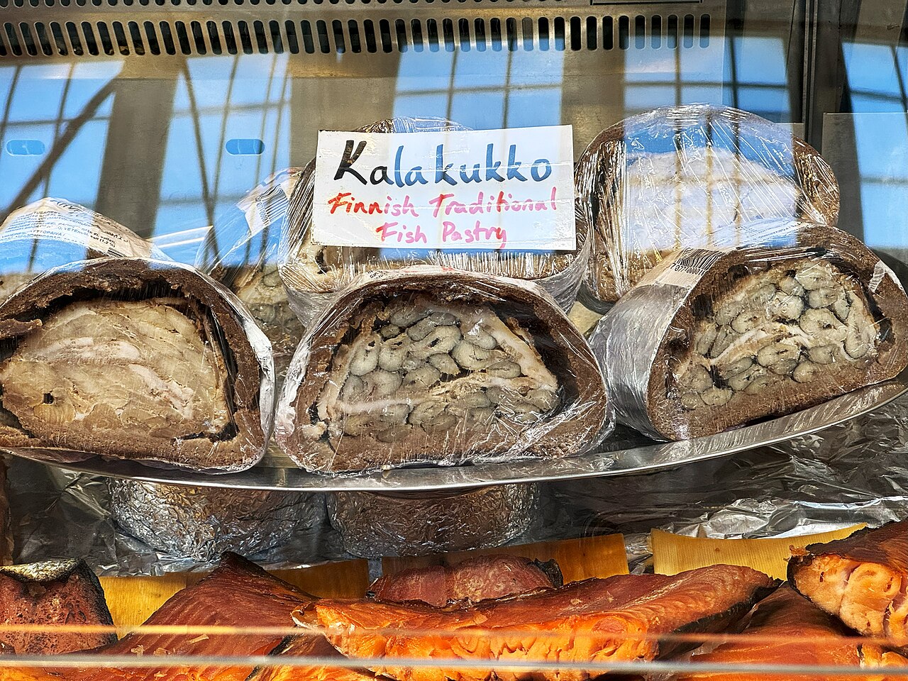市場の店頭に並ぶ、半分に切って中の魚が見えるカラクッコと手書きの札