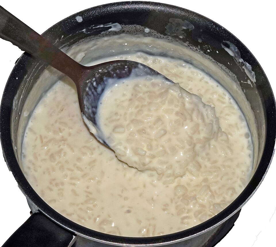 鍋の中でスプーンでかき混ぜられている、牛乳で炊いた米の粥