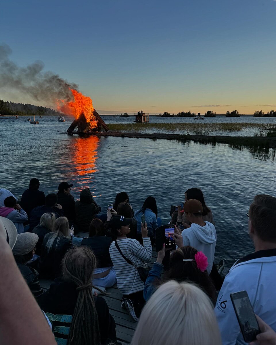 2024年、ヨエンスーの湖畔で燃える夏至祭の焚き火と、それを見つめる人々