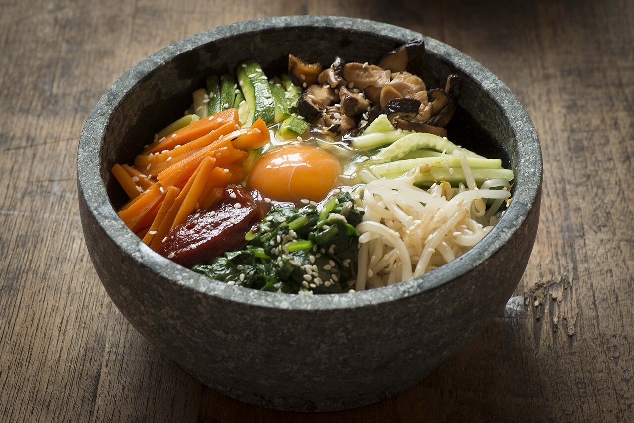 野菜を彩りよく並べた石焼きビビンバ。中央の卵と赤い薬味が目を引く。