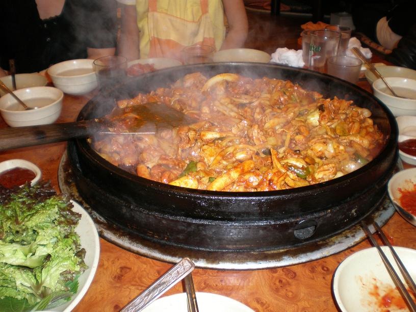 卓上の大きな鉄板で、鶏肉と野菜を調理する。