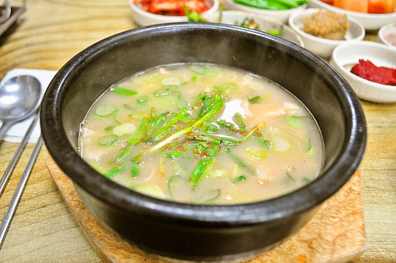 ニラを添えたテジクッパ。白い汁と豚肉に青い薬味を合わせる。