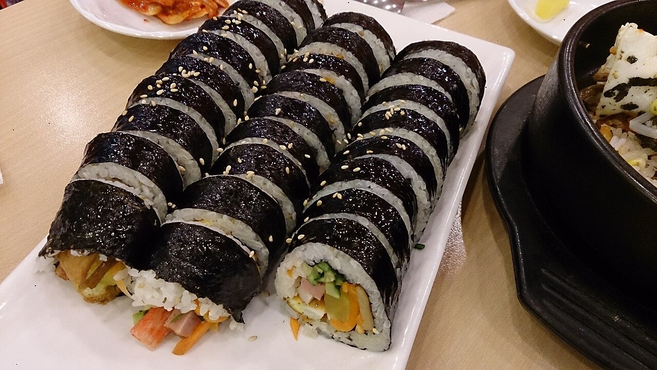 断面を見せて並べたキンパ。ご飯、海苔、色の違う具が重なる。