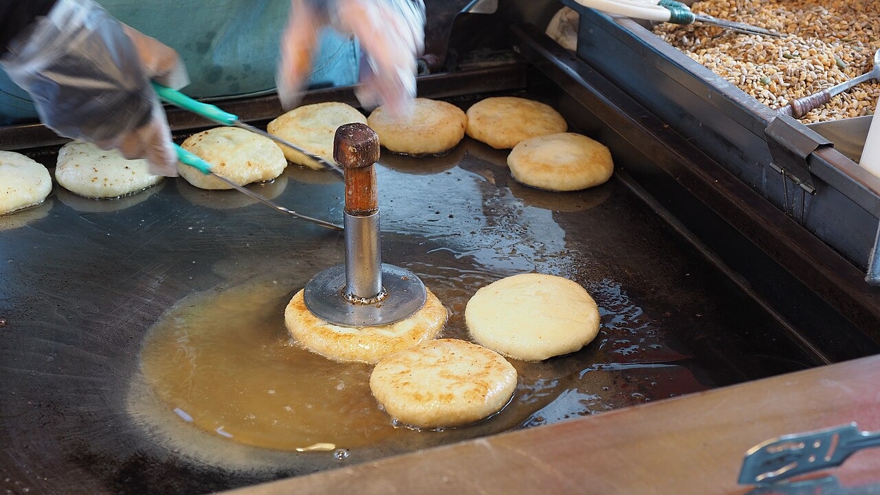 釜山で、鉄板と押し器を使って焼くホットク。