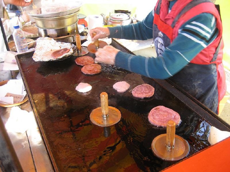 露店でホットクの生地を包み、焼くところ。