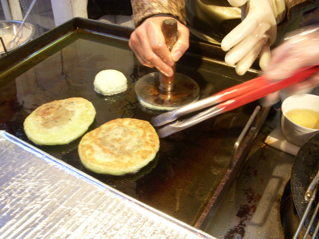 専用の押し器で生地を平たくする、焼き台の作業。
