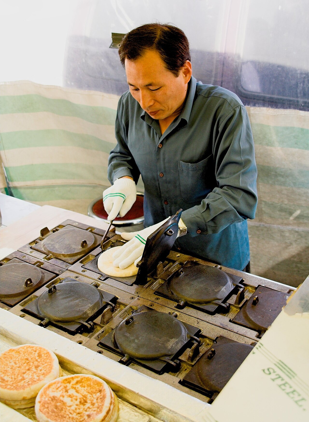 ホットクの生地を道具で押して焼く売り場の仕事。