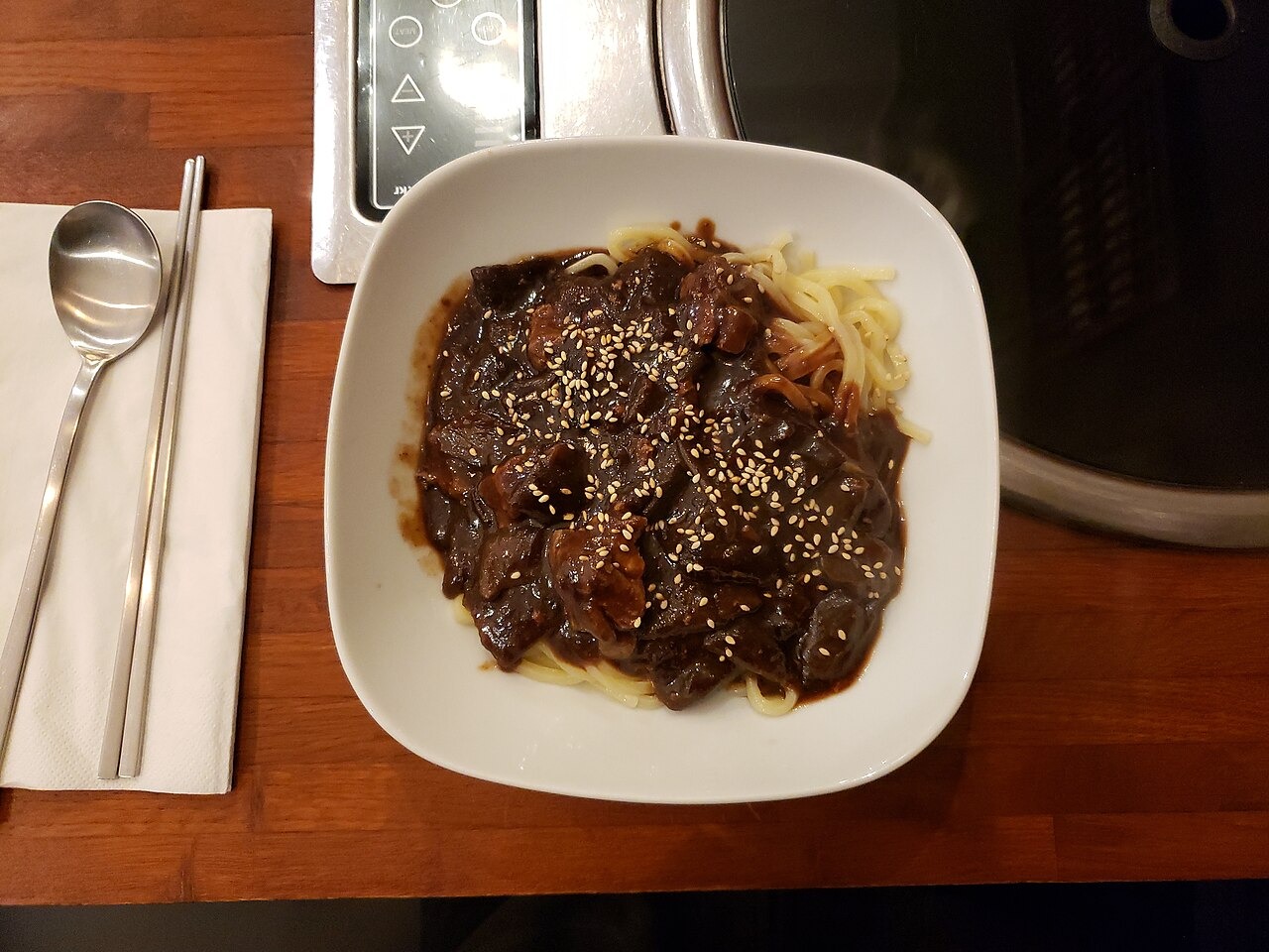匙と箸を添えて食べる、韓国式の黒いたれの麺。