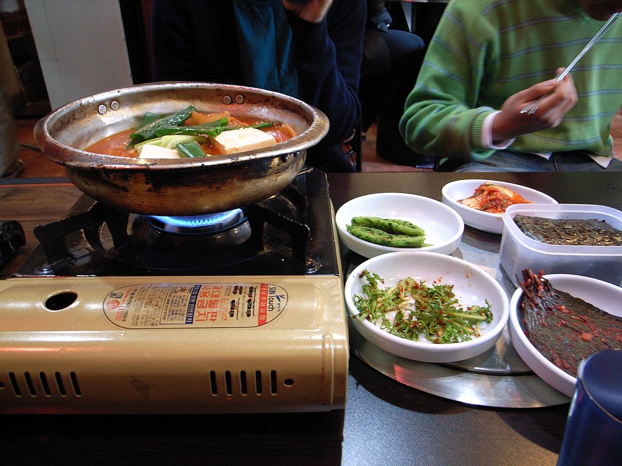 卓上の火で煮るキムチチゲを囲んだ食卓。