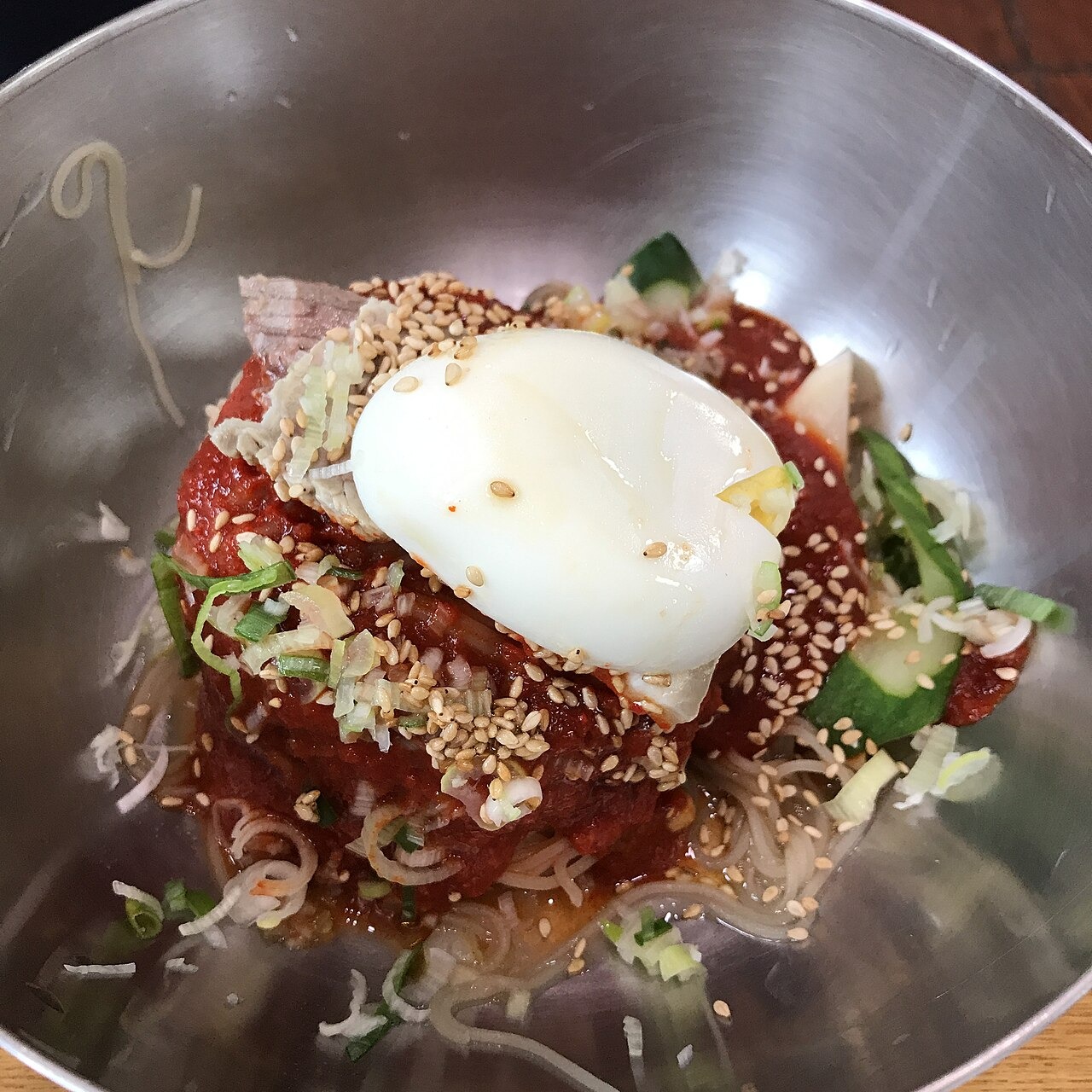 辛いたれを絡めて食べる、卵付きのビビン冷麺。