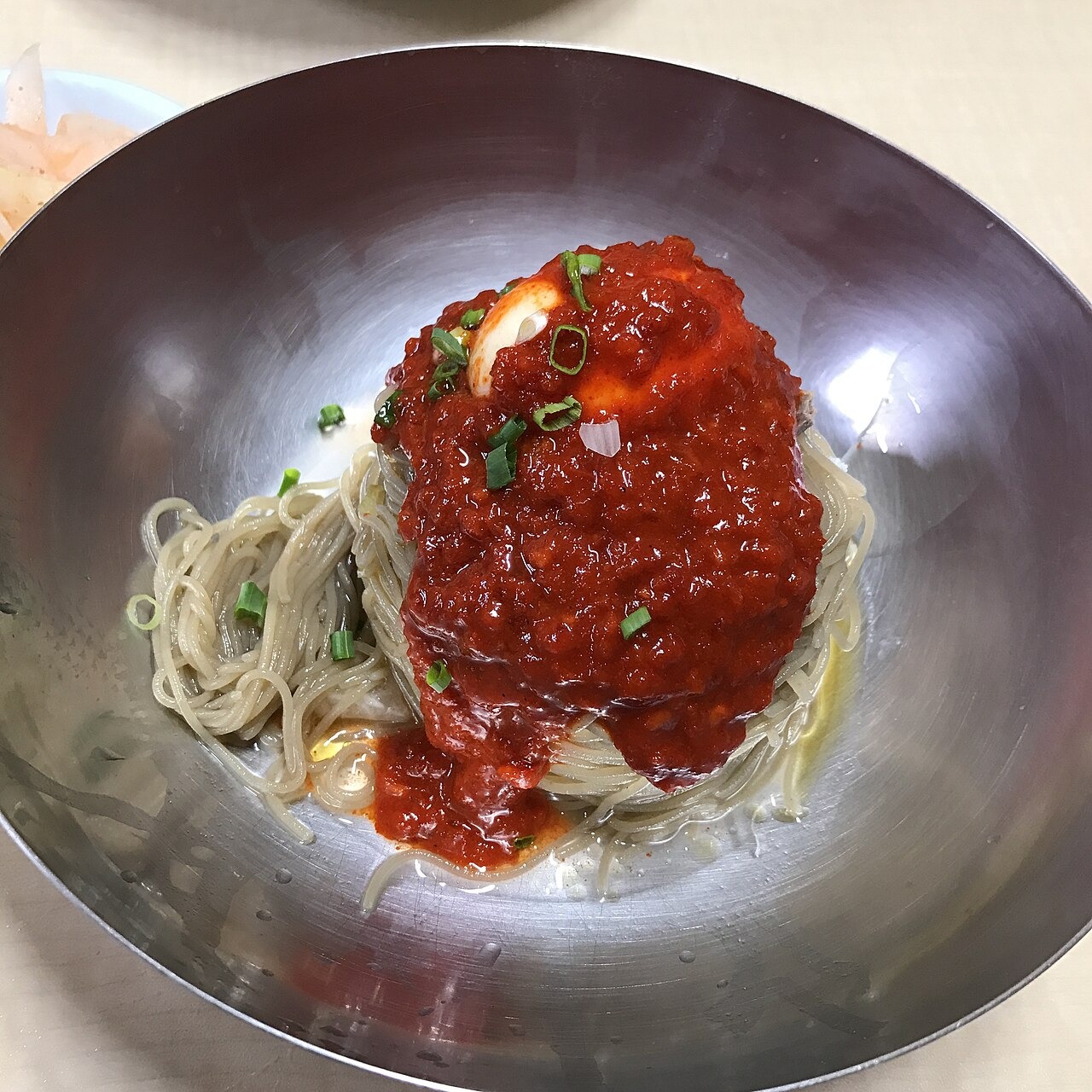 麺の中央に赤いたれをのせた冷麺。