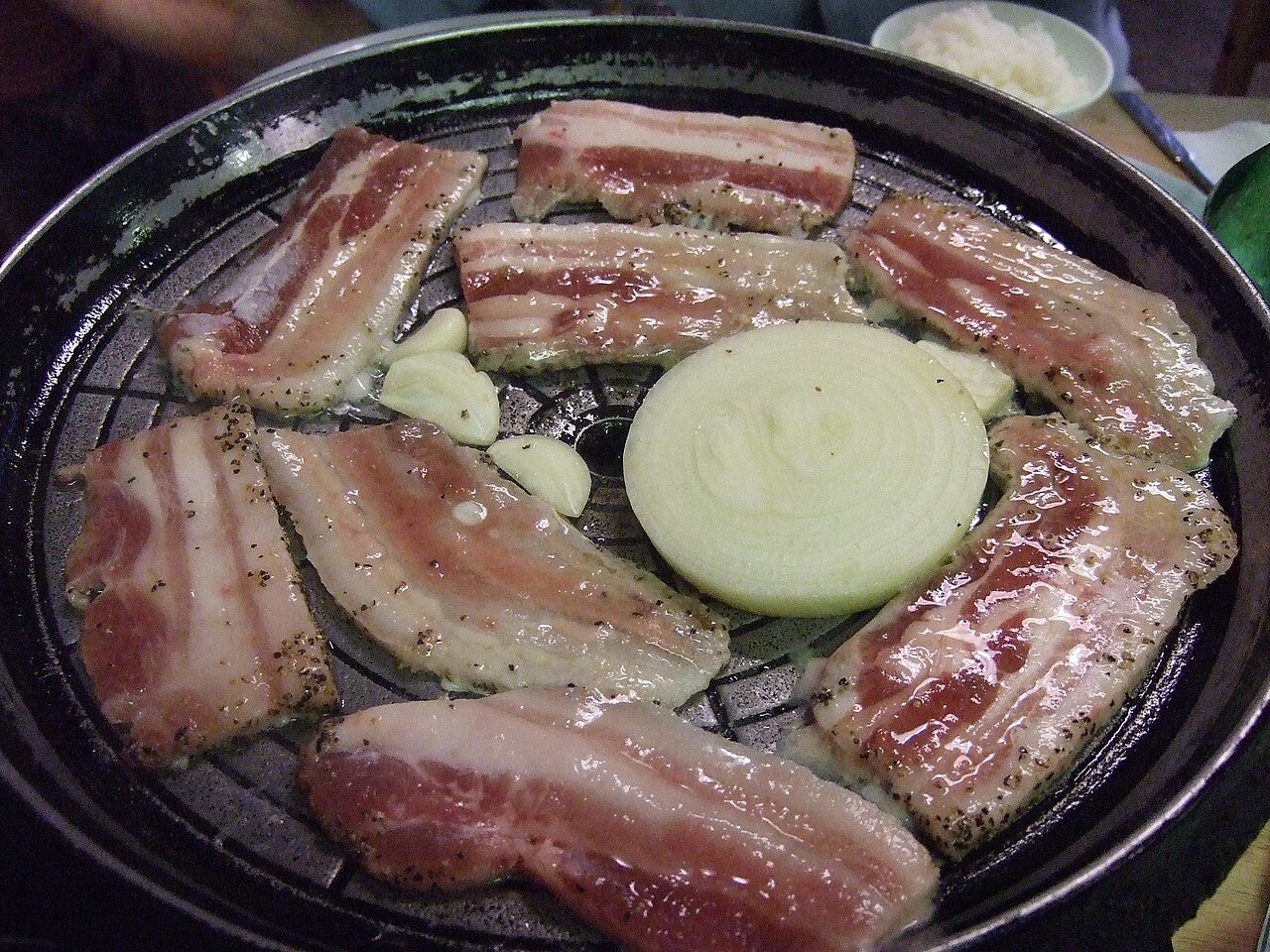長い豚バラ肉を焼き台で加熱するところ。