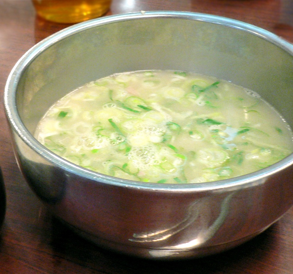 ねぎを添えた、乳白色の牛骨スープ。