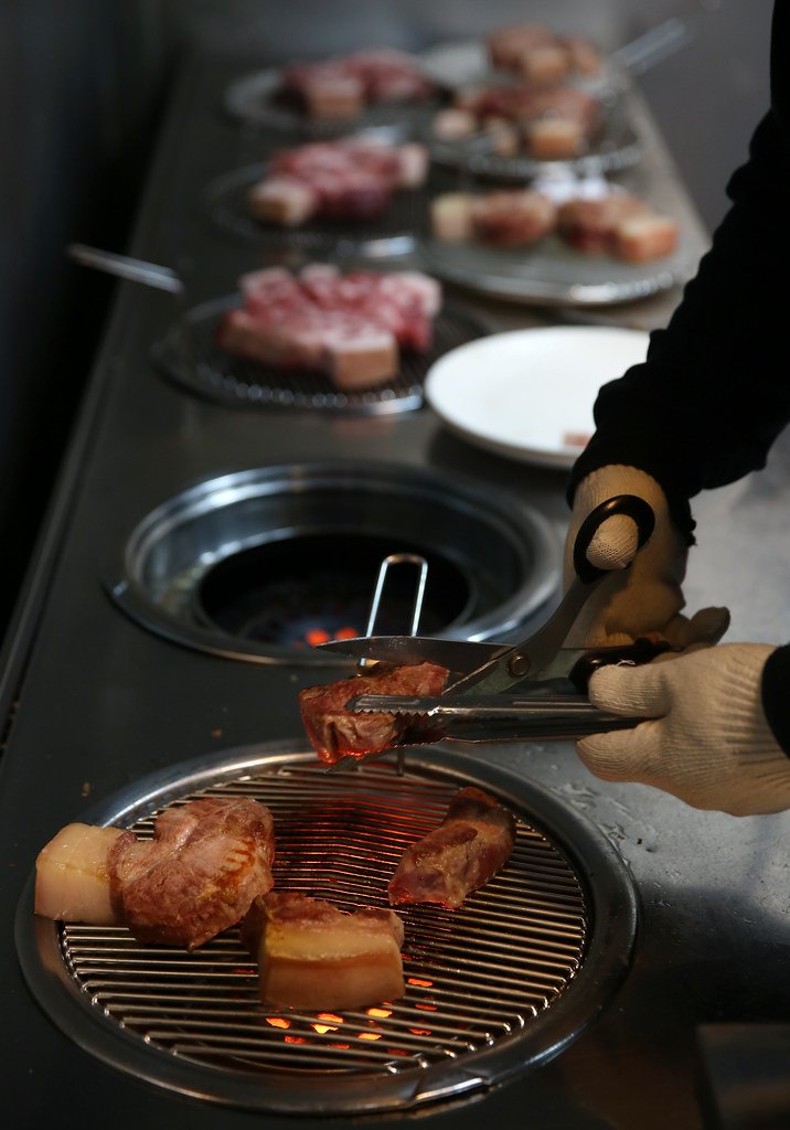 鉄網の上で豚肉を切り分ける。