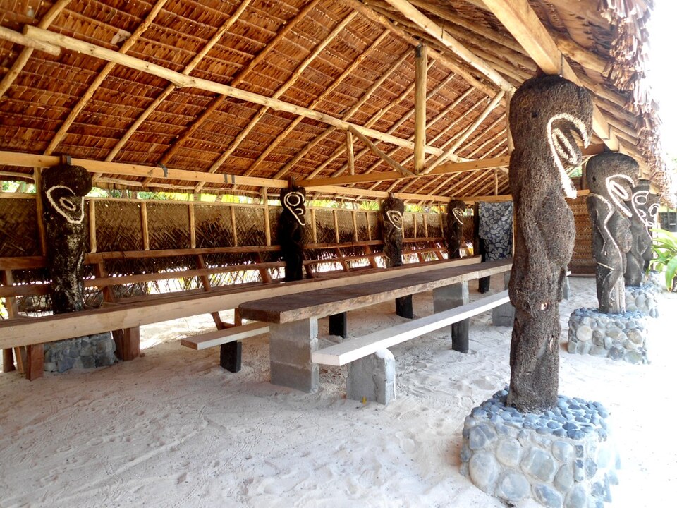 茅葺き屋根と長いベンチ、彫刻を施した柱が並ぶナカマルの内部