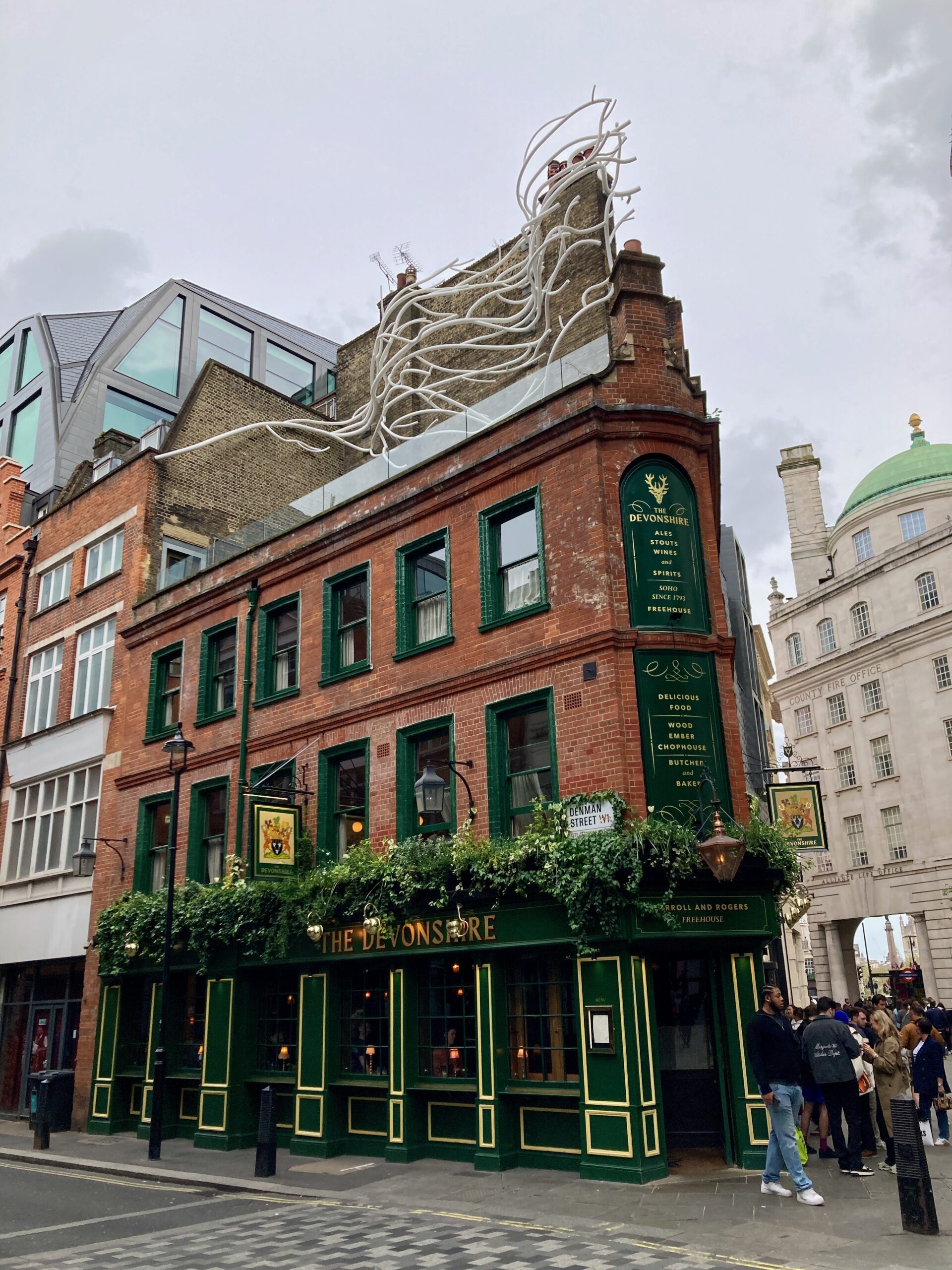 ソーホーのパブ The Devonshire の角の建物（赤レンガ、緑の窓枠、植え込み）