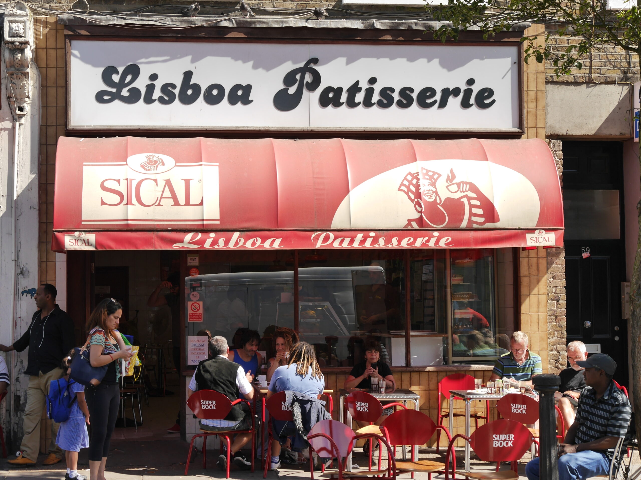 Golborne Road の Lisboa Patisserie の店先。赤い日よけとテラス席の客