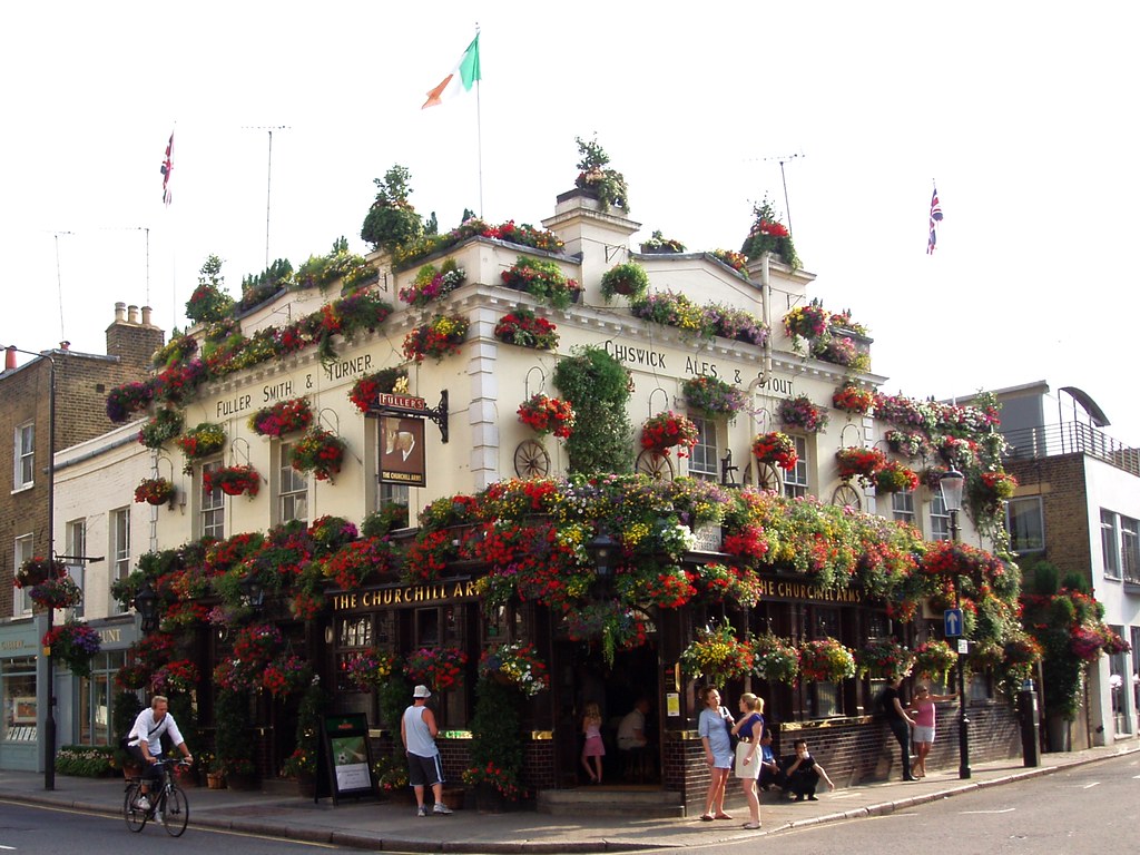 花で覆われた The Churchill Arms（ケンジントン）の外観、角地の全景
