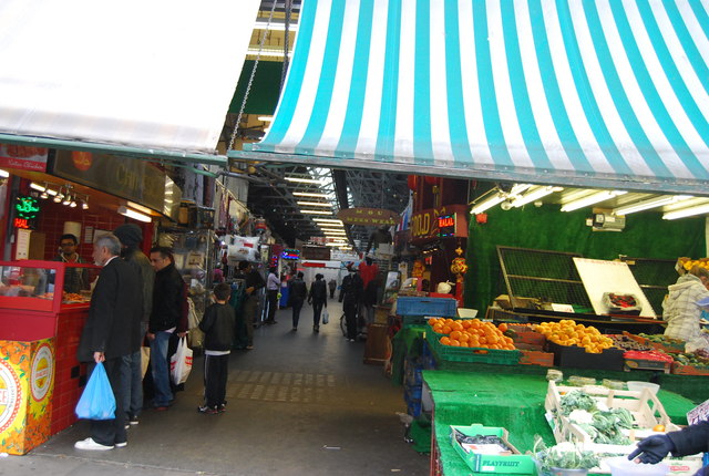 赤と白の外壁に「TOOTING MARKET」の文字、青果の店先と行き交う人