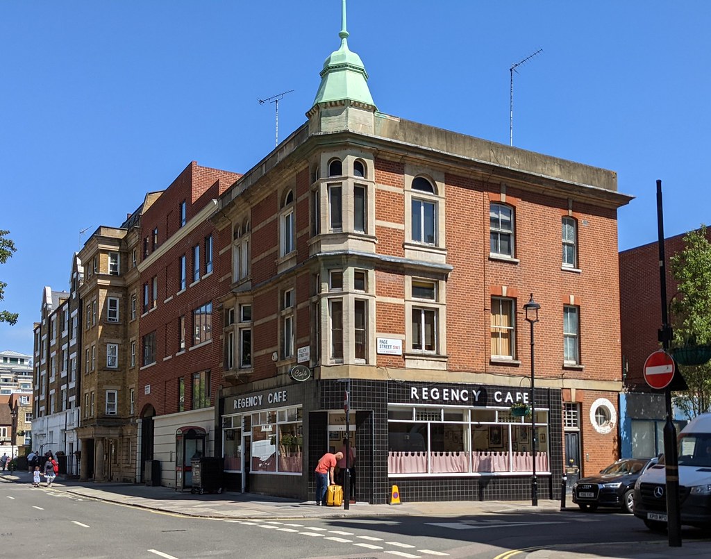 青空の下、ピムリコの交差点の角に建つ赤れんがの建物と1階のRegency Cafe