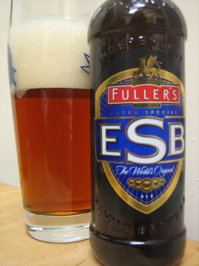 パイントグラスに注いだ赤銅色のエールと、Fuller's ESBの瓶のラベル