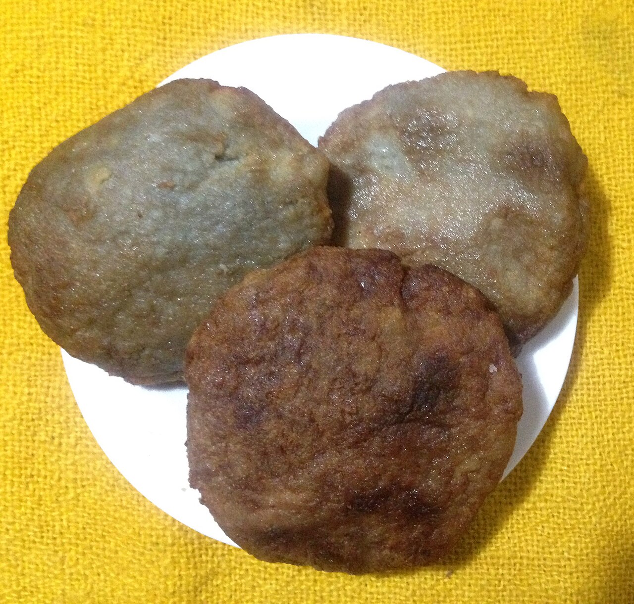 黄色い布に置かれた白い皿の上の、焼き色の異なる三枚のミルカオ